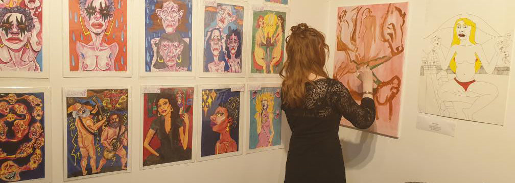 Woman painting an artwork on a wall at an art exhibition